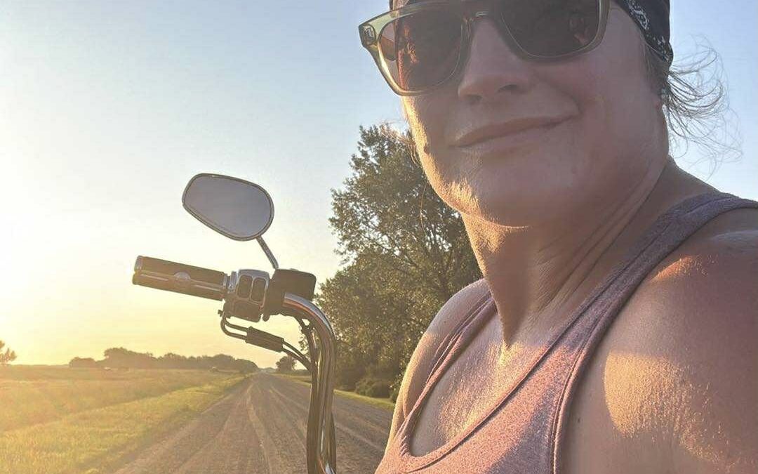 Empowered woman sitting on motorcycle in sunset